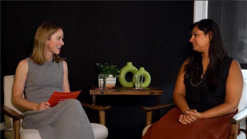 Two woman sitting in chairs facing each other in an interview style