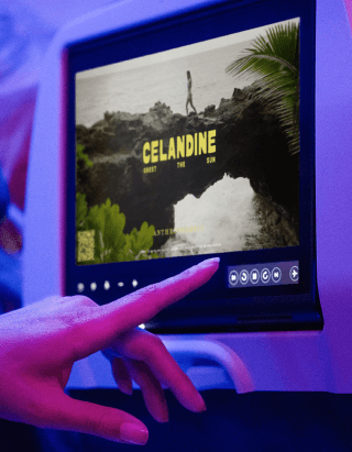 A traveler interacts with inflight entertainment content on a seatback screen.