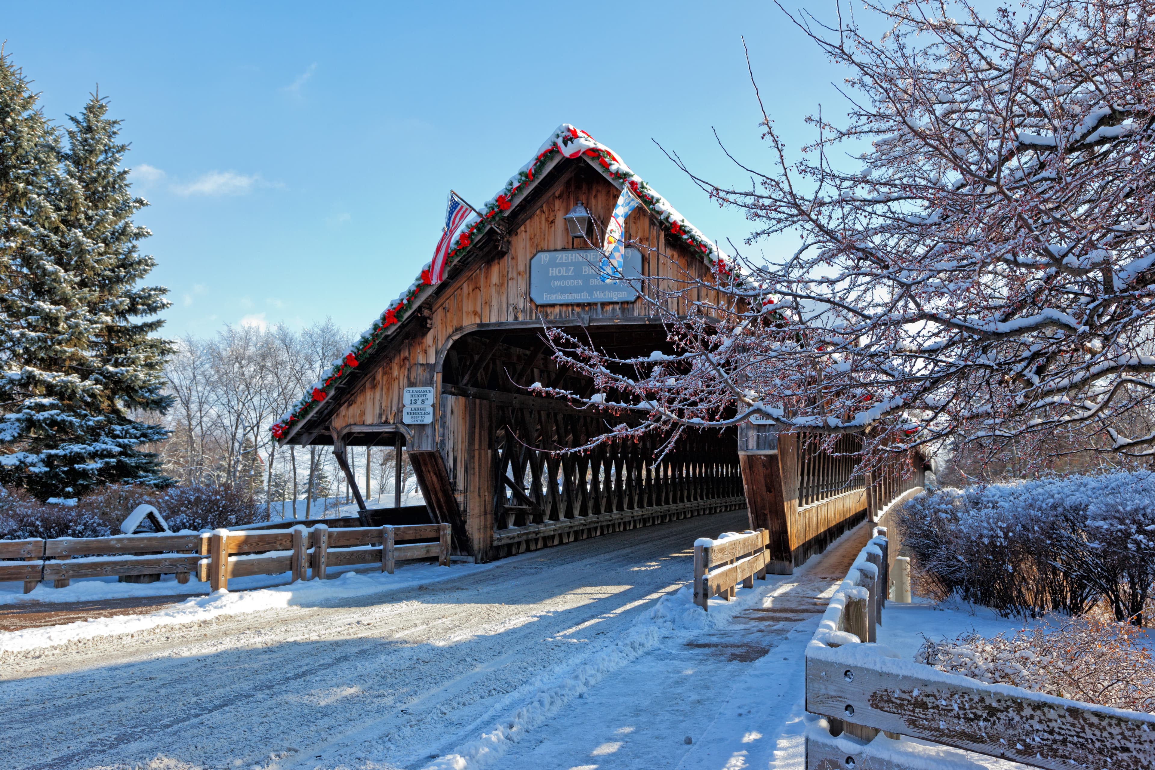 Snow-covered cabin in a winter landscape with bare trees
