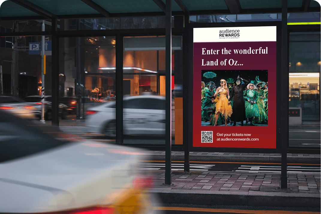 Digital travel advertisement displayed at a bus stop on a city street at night.