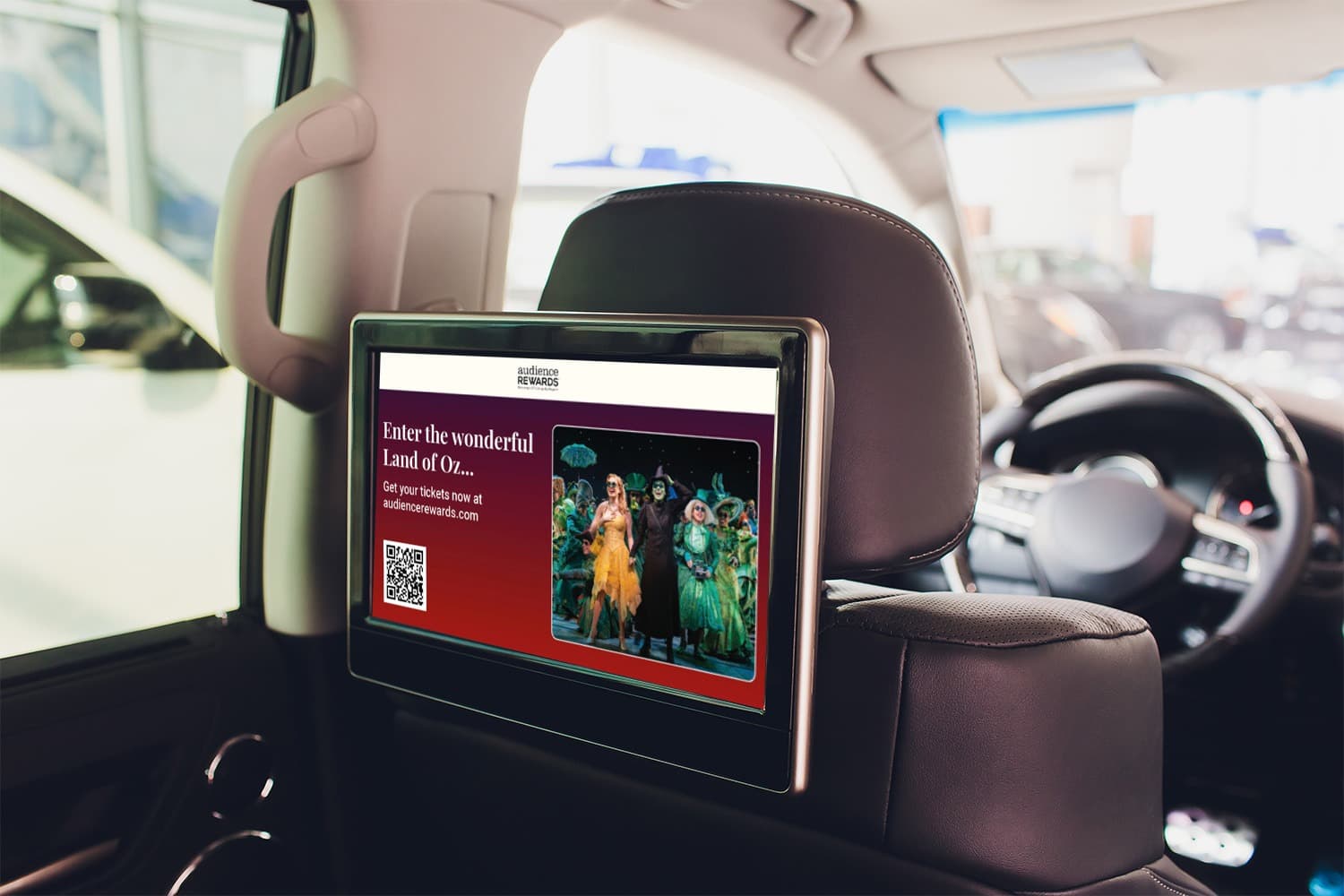 A  close up photo of a seatback display attached to the back of the drivers seat, inside of a car
