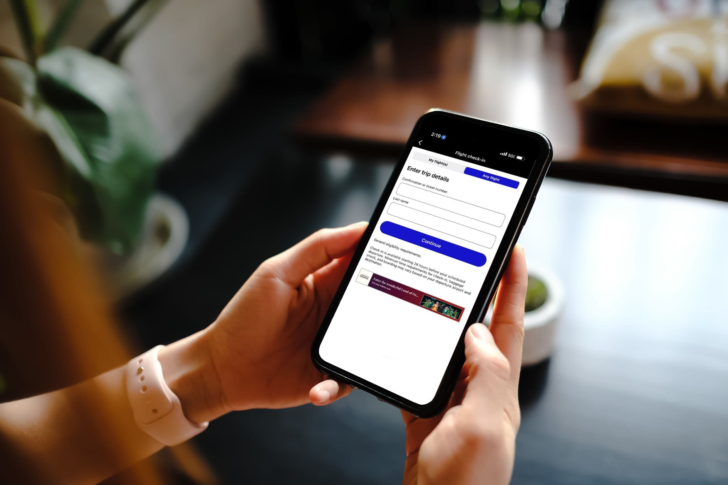 A person holding a mobile phone with both hands while checking real-time updates on the screen