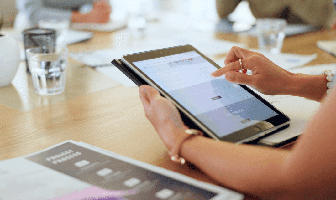 A person at a table typing on their tablet.