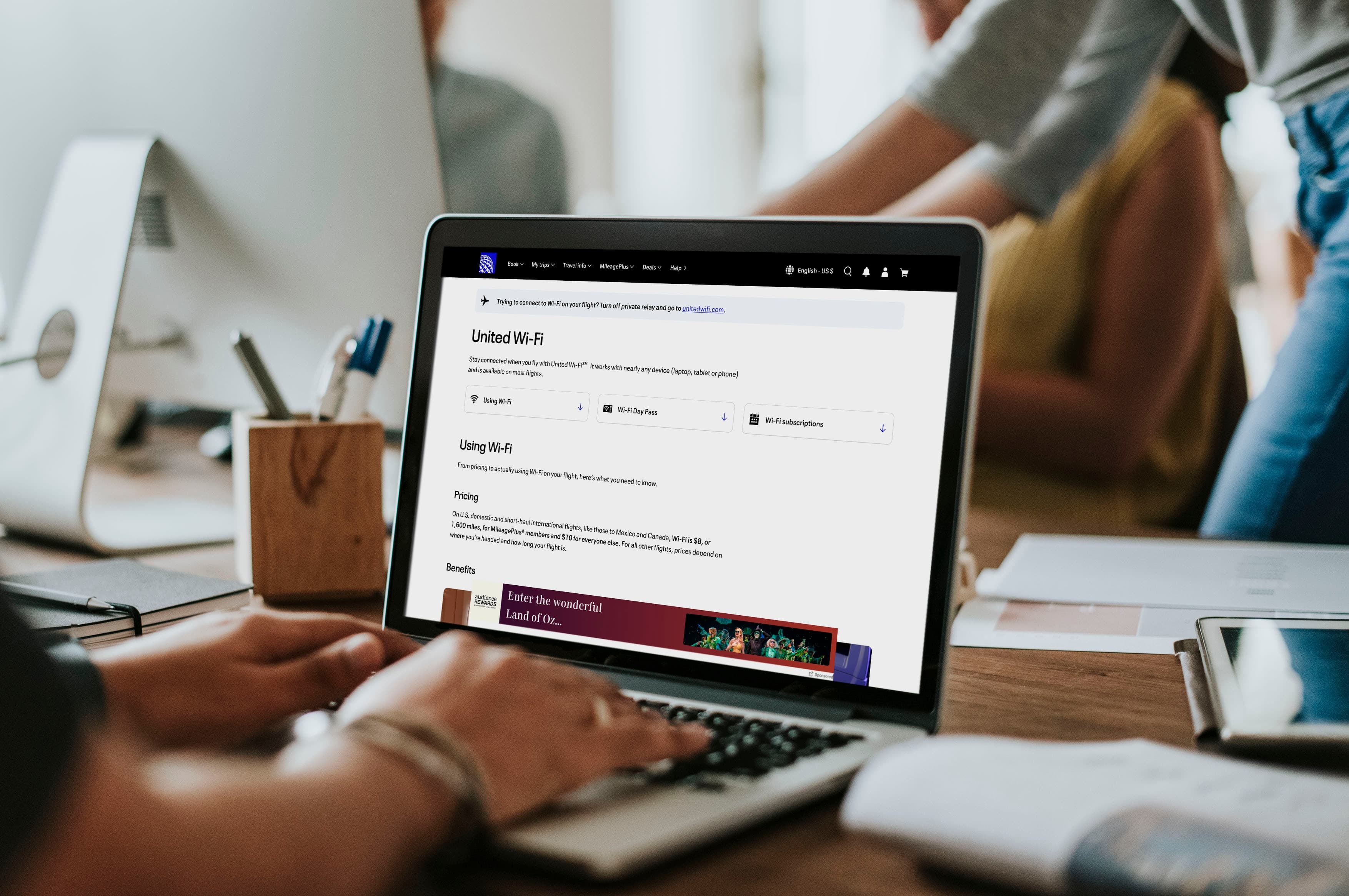 A person at a desk typing on their laptop computer