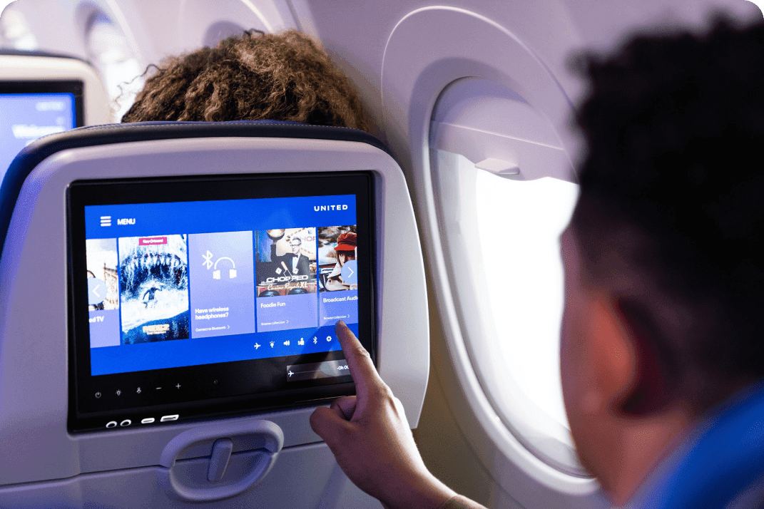A man on a plane making choices on a seatback display.