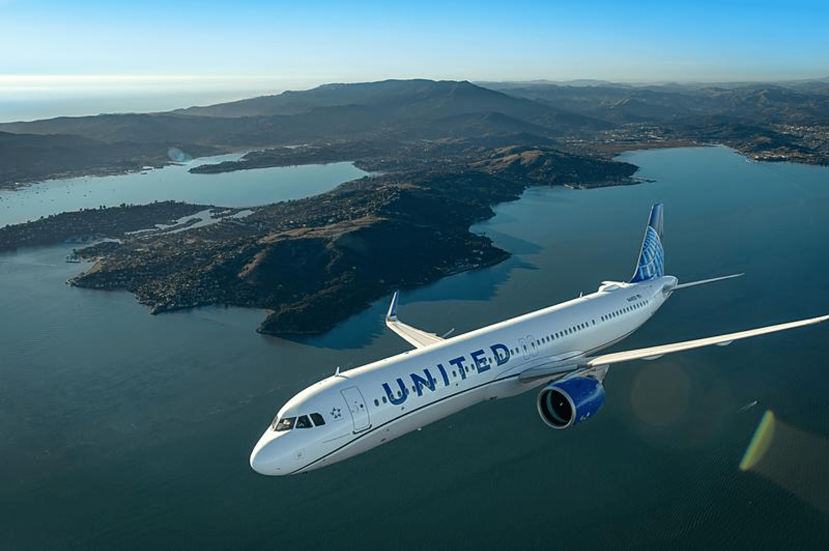 A United plane flying above mountains.
