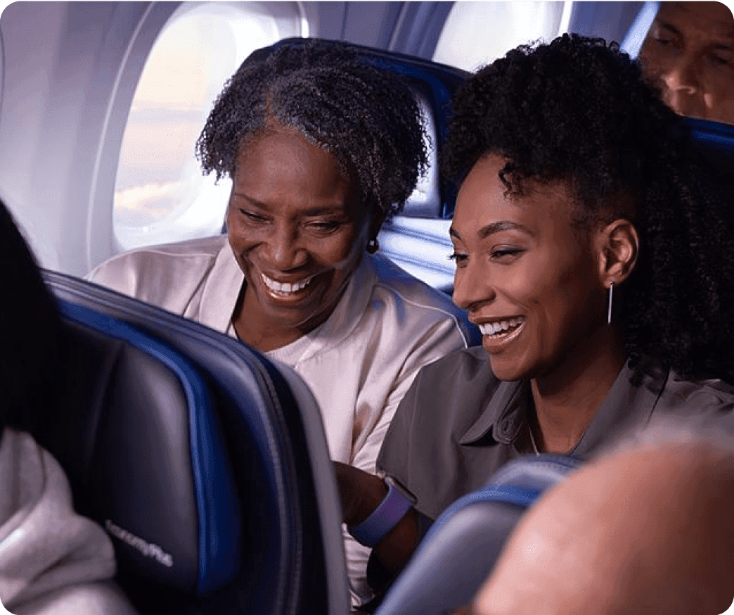 Two travelers smiling at a inflight entertainment screen on their plane.