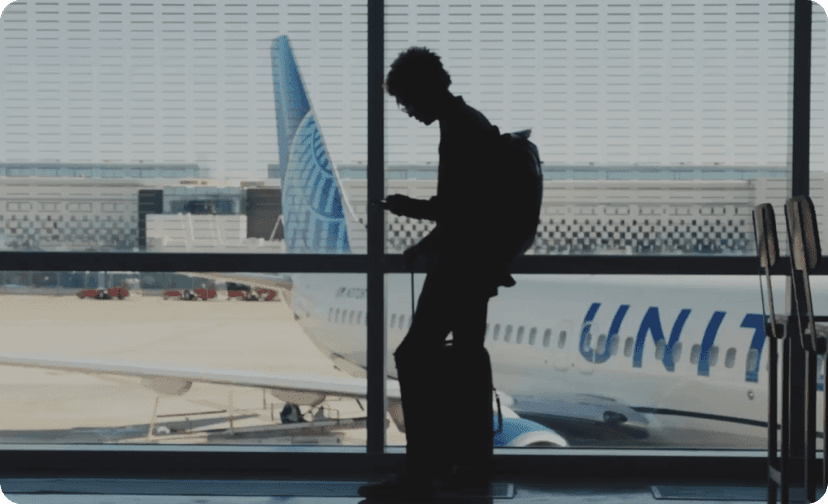 Silhouette of a person standing at an airport window overlooking a United Airlines plane on the tarmac